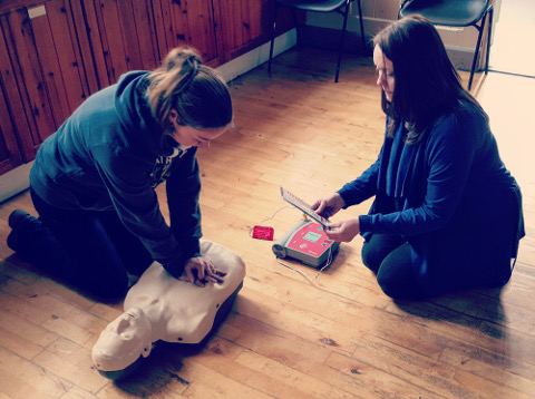 A student of a first aid course using an AED