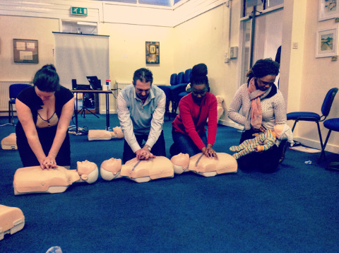 Students of a first aid course giving CPR compressions to training manikins